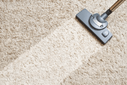 Cropped view of hands holding vacuum cleaner of Caucasian female cleaning service worker vacuums rug in living room kitchen. Concept of cleaning and disinfection in modern apartments.